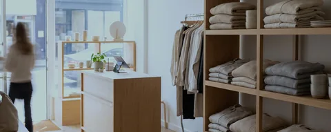 A bright boutique clothing shop with folded knitwear on wood shelving