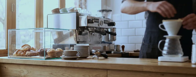A coffee shop counter with an espresso machine and a pastry case