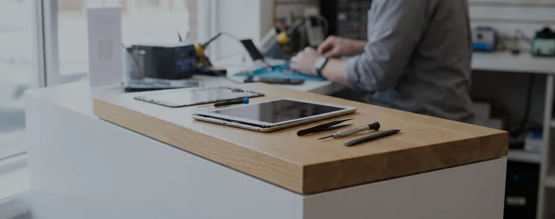 A small electronics repair counter with a tablet and tools
